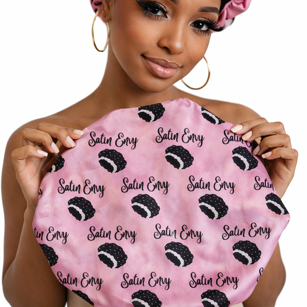 Woman holding a pink satin cap with black pattern and &