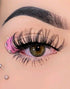 A close-up image of a person wearing pink diamond-shaped false eyelashes with bejeweled accents.