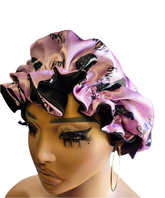 Mannequin head wearing a pink satin bonnet with black bonnet patterns on a white background