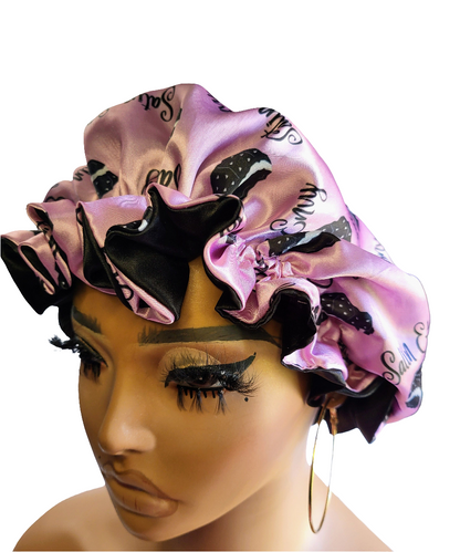 Mannequin head wearing a pink satin bonnet with black bonnet patterns on a white background