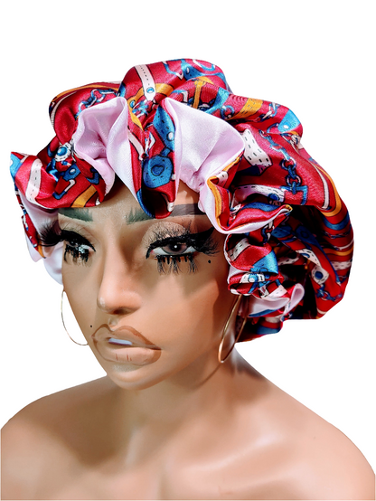 A mannequin head wearing a multicolored reversible satin hair bonnet with a red and blue pattern on one side and a plain white satin bonnet on the other.