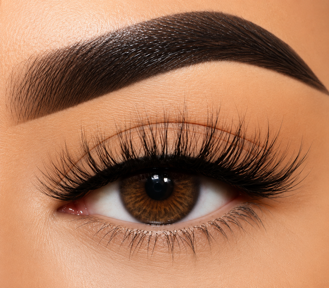 Extreme close-up of a human eye with long, curled false eyelashes, a defined dark brown eyebrow, and a brown iris, shown on skin.