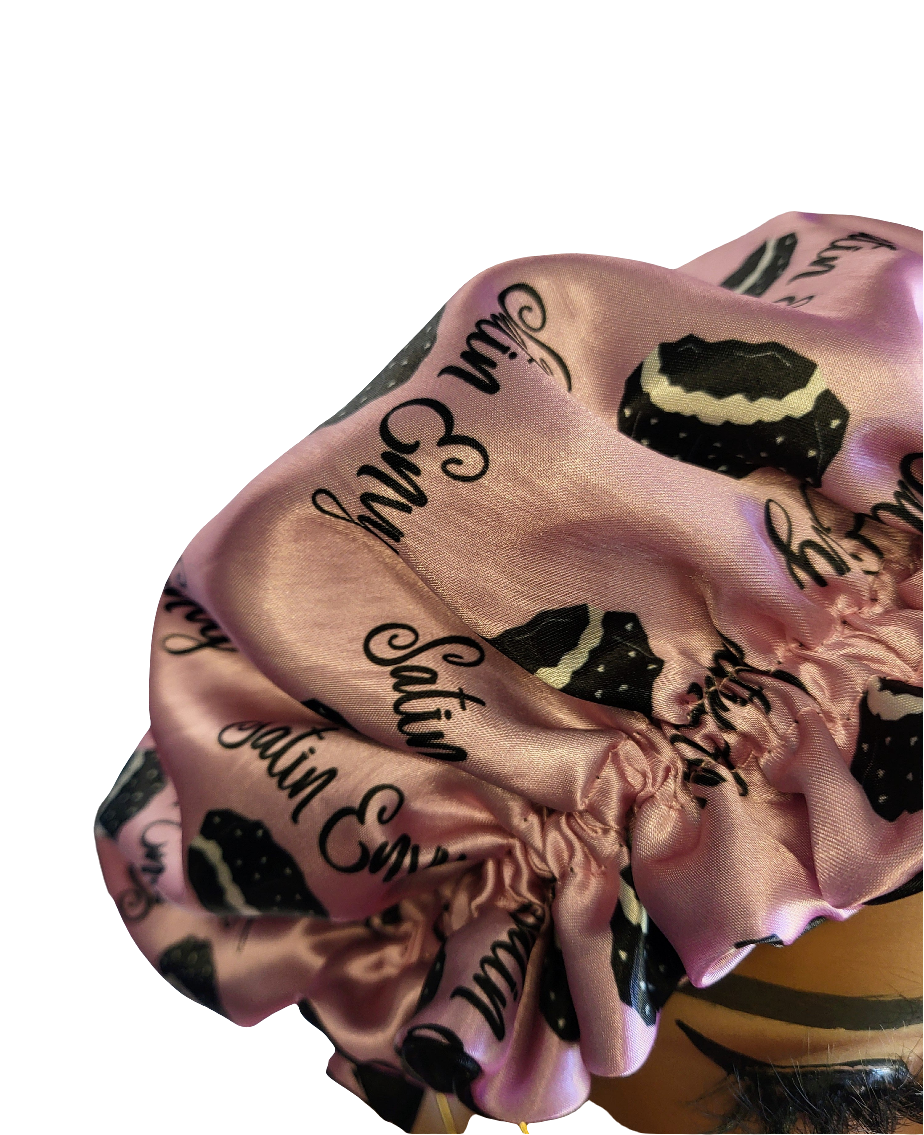 Pink satin bonnet with black text and patterns on a white background