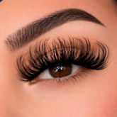 Close-up of an eye with long, dark eyelashes on a neutral background