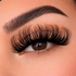 Close-up of an eye with long, dark eyelashes on a neutral background