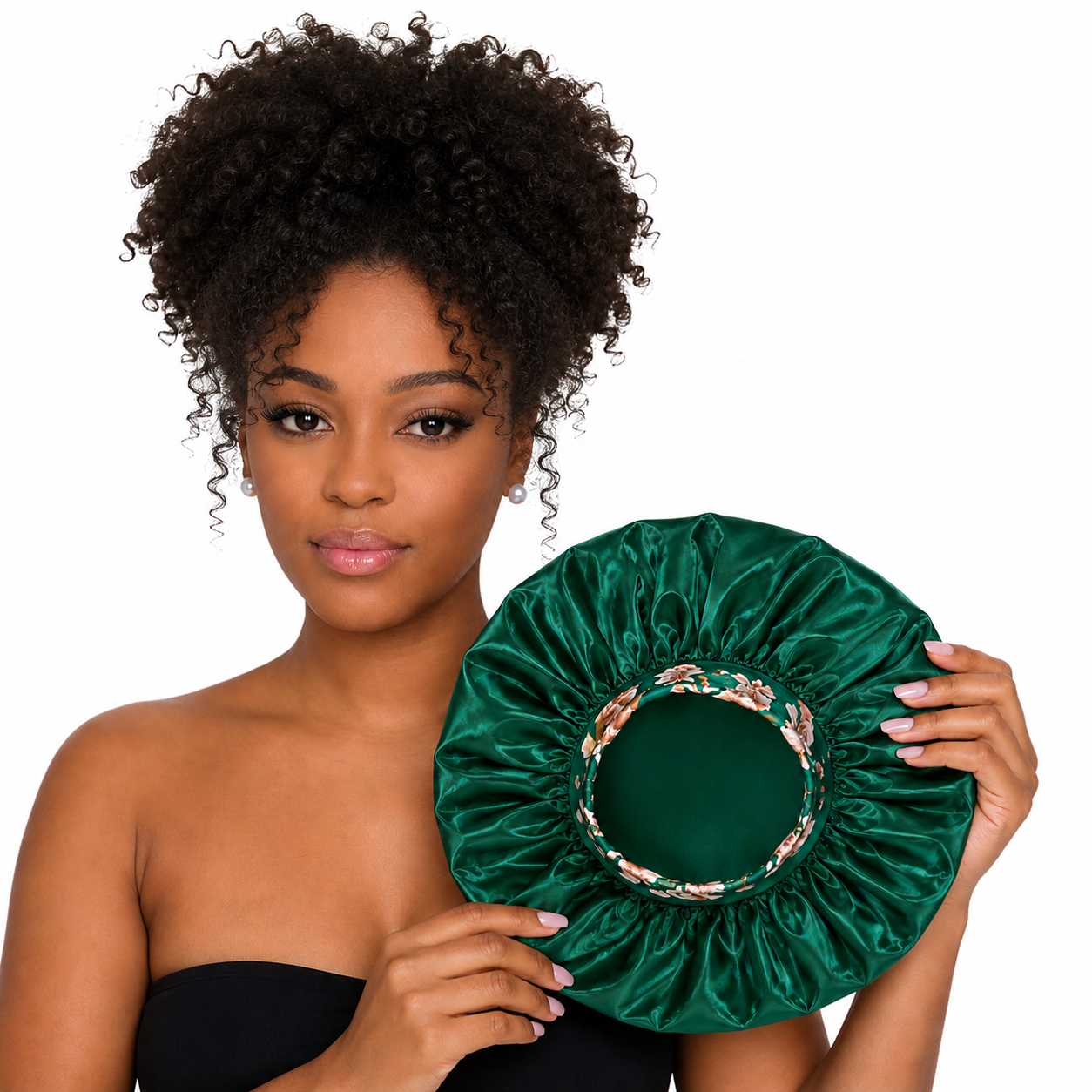 Woman holding a green satin bonnet with floral lace trim against a white background
