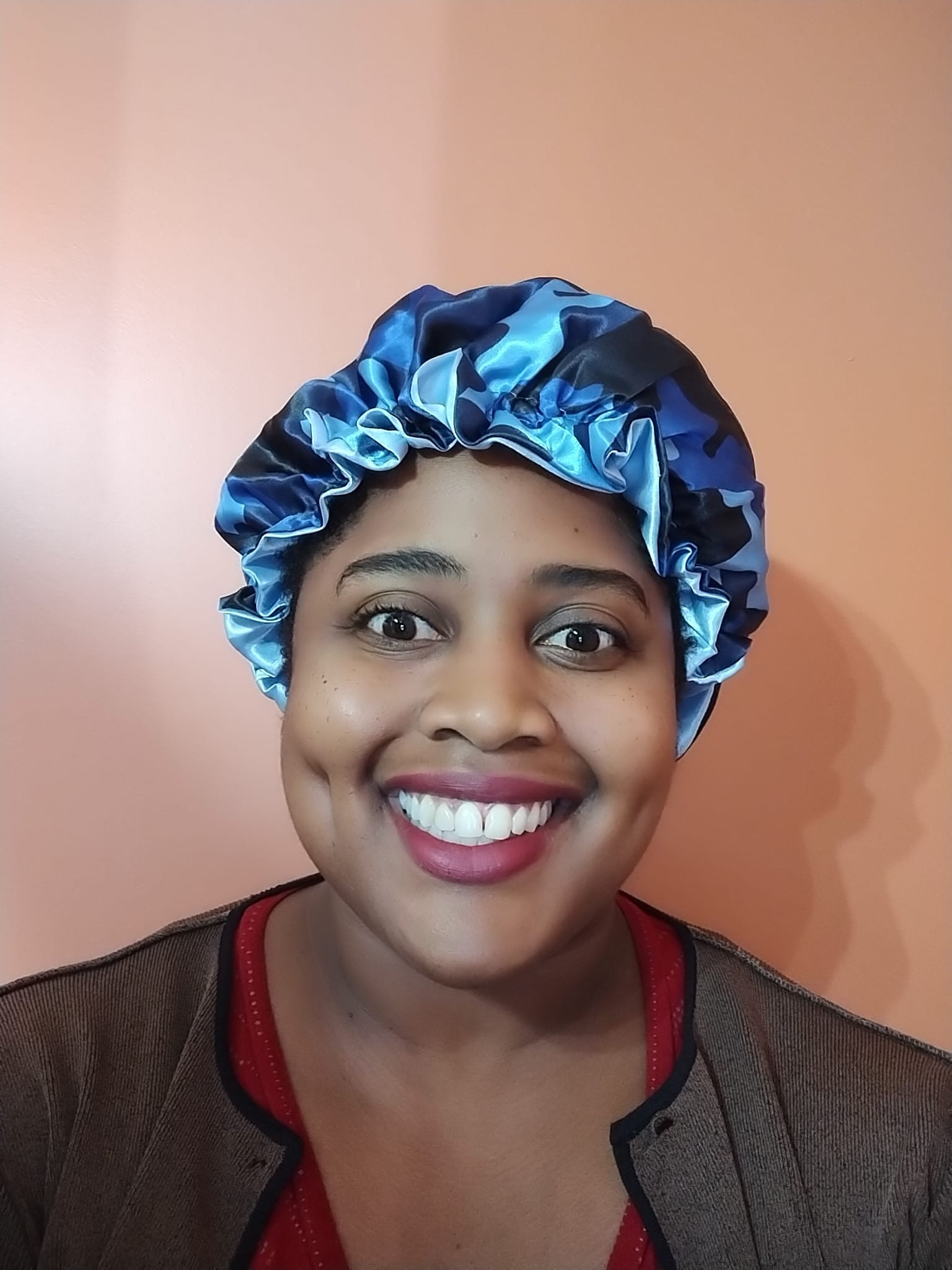 Person wearing a blue satin bonnet against a pink background