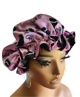 Pink satin bonnet with black bonnet designs on a mannequin head.