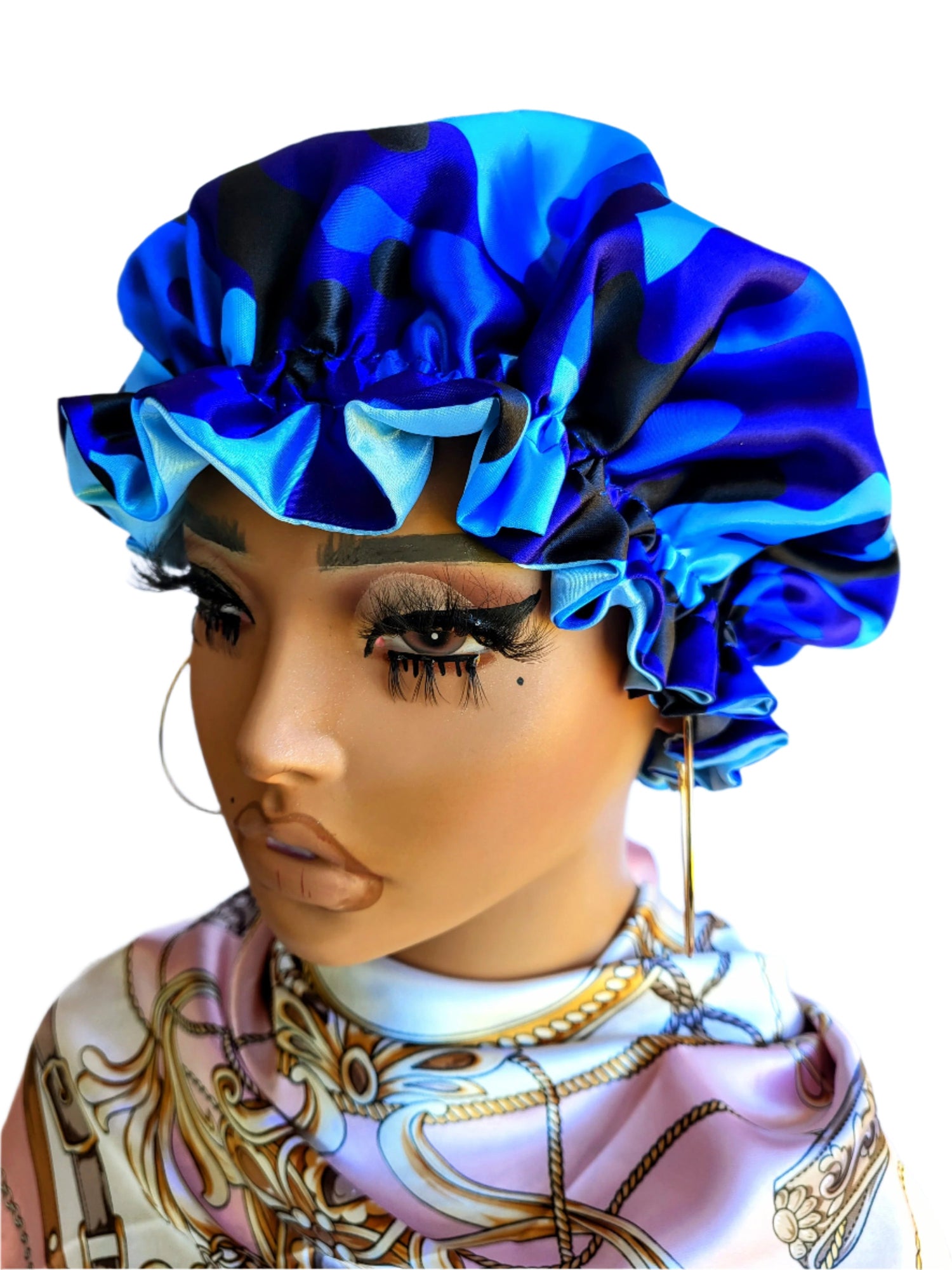 A mannequin head showcasing a reversible sleeping satin hair bonnet with a vibrant blue camo print on one side.